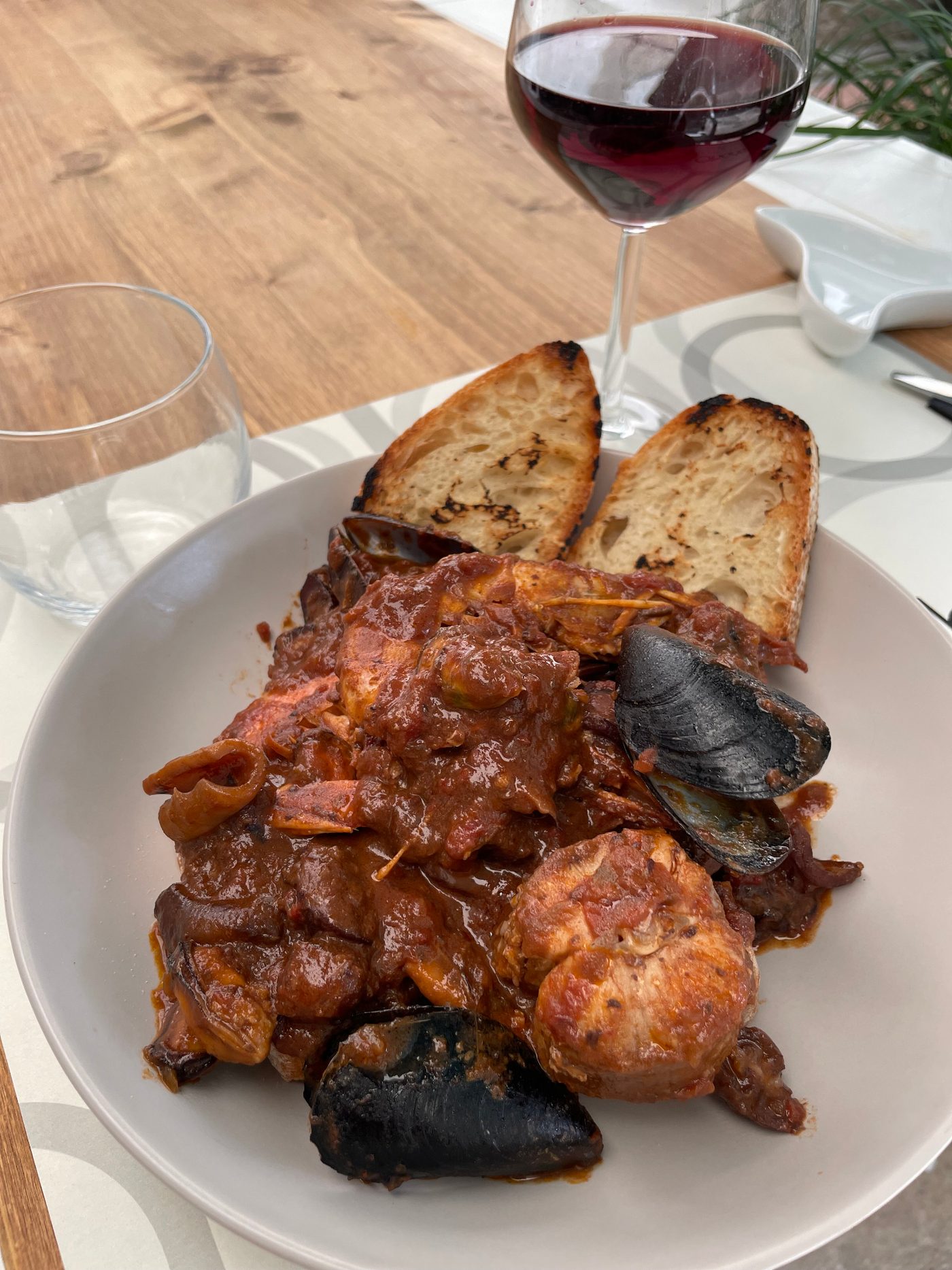 Cacciucco di pesce con crostoni di pane abbrustolito e calice di vino rosso